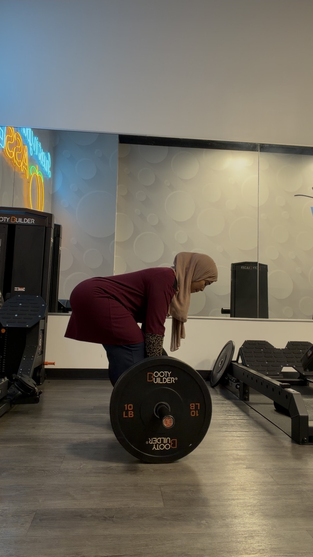 Coach Assia setting up for a barbell Romanian deadlift with a loaded barbell